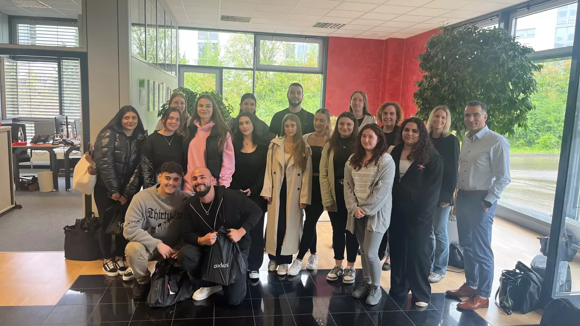 Gruppenfoto von jungen Menschen und Mitarbeitenden in einem Bürogebäude – Besuch einer Schulklasse bzw. Gruppe bei audius.