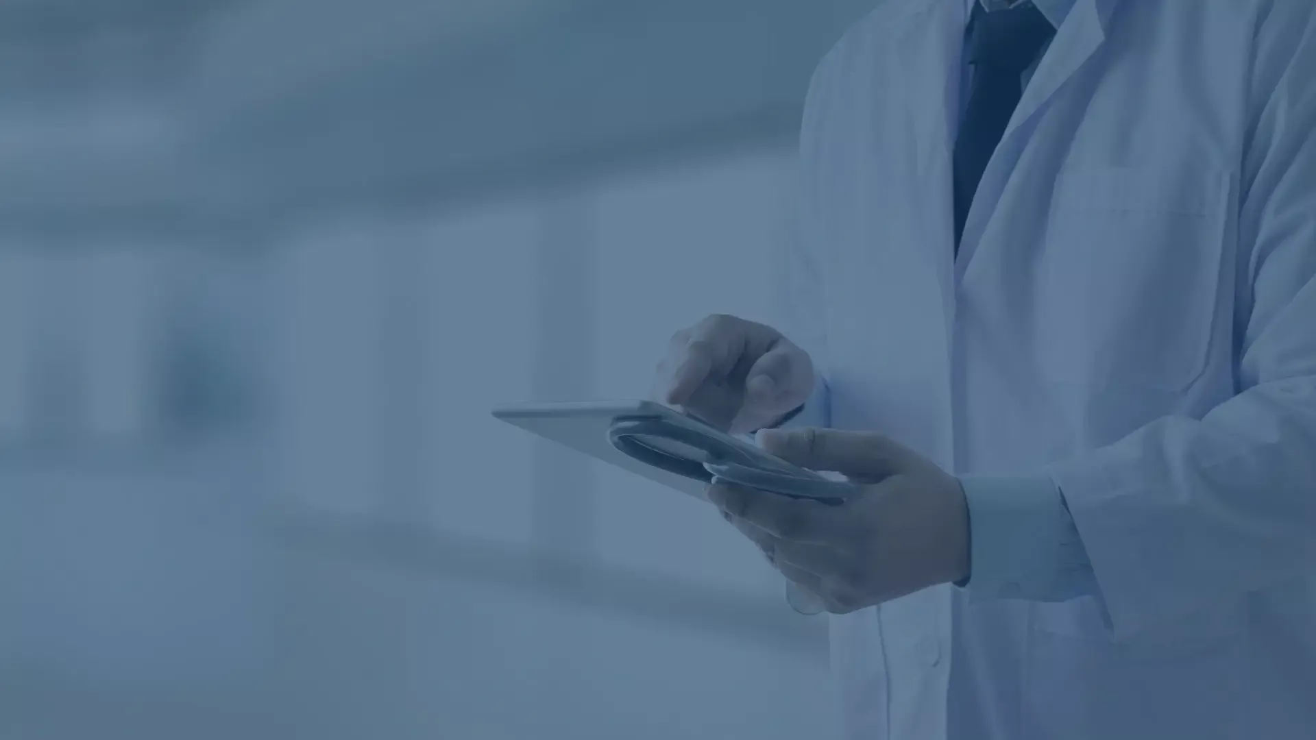 Arzt in weißem Kittel bedient Tablet in modernem Krankenhausflur zur digitalen Patientenakte.