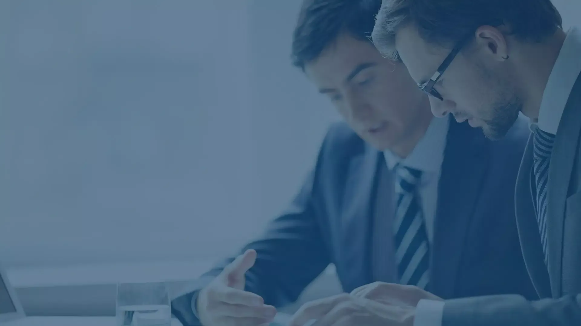 Zwei Business-Männer in Blautönen diskutieren in einem modernen Büro, Symbol für professionelle Zusammenarbeit und Geschäftsgespräche.