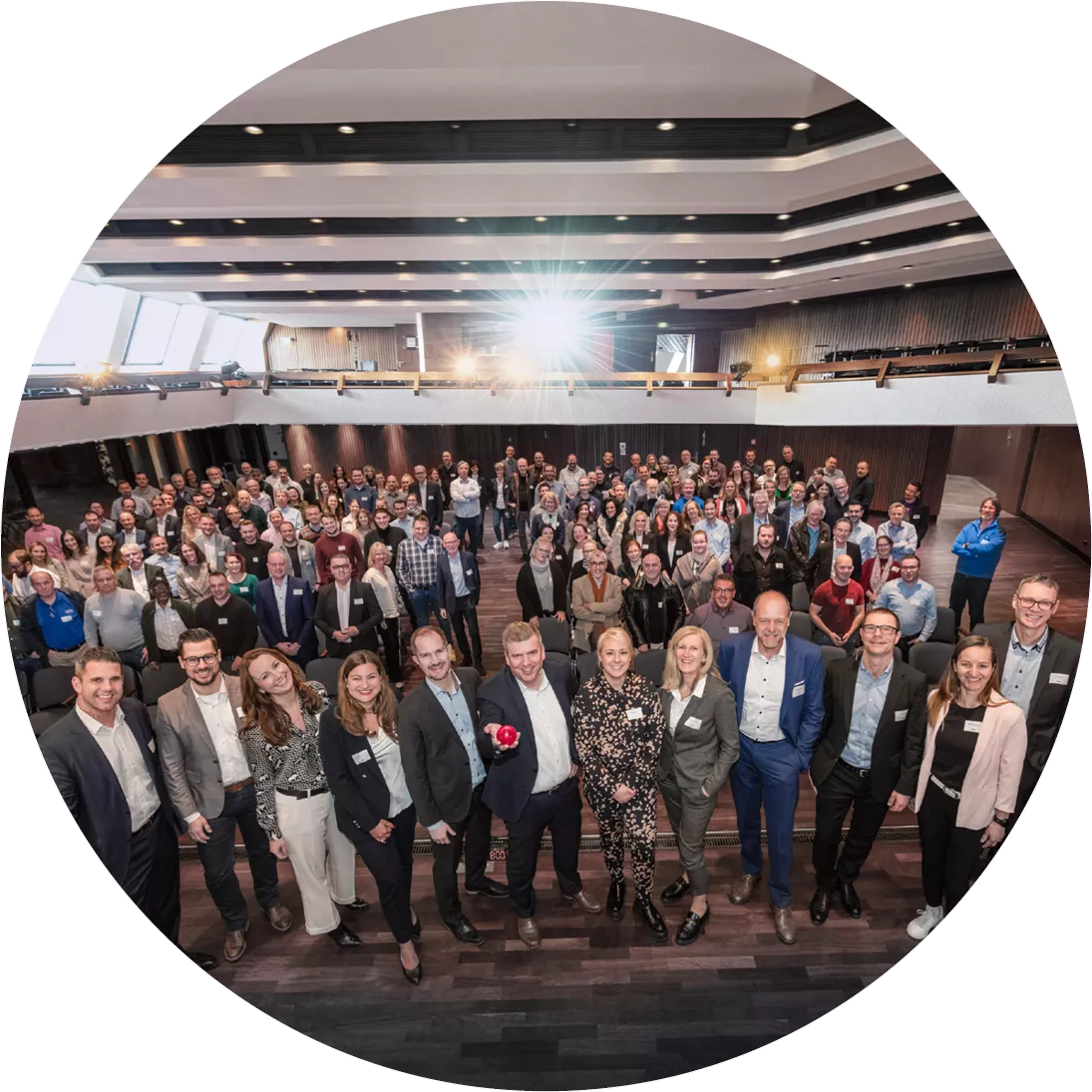 Große Gruppe von audius Mitarbeitern und Führungskräften bei einer Firmenveranstaltung in einem modernem Auditorium – Symbol für Teamgeist und Qualitätsversprechen.